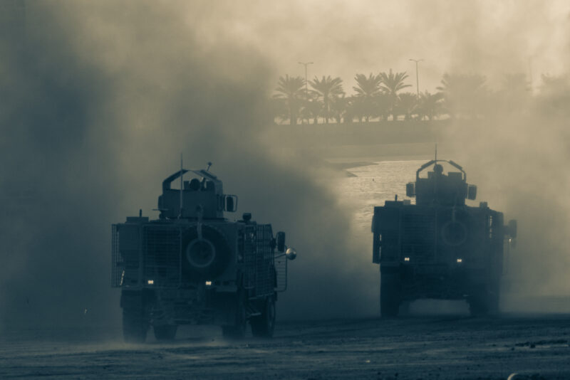 Military chopper and army vehicles flying and driving entering into the smoke and war Military concept of power force strength air raid explosion