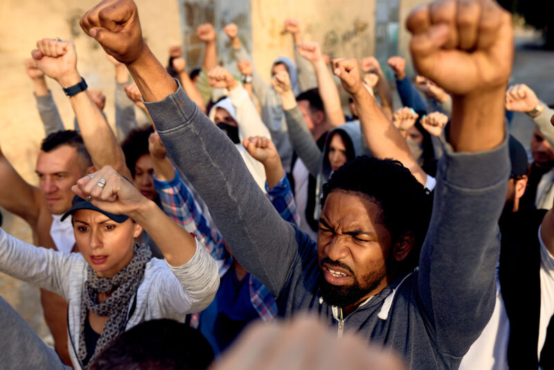 Displeased African American man with raised fists protesting with group of people